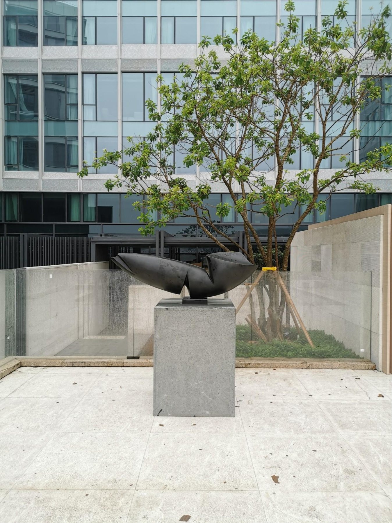 Dark sculptural form on a plinth within hotel landscaping