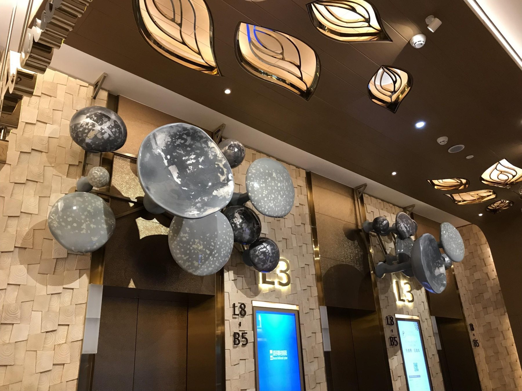 Reflective circular wall art installed above K11 elevator doors