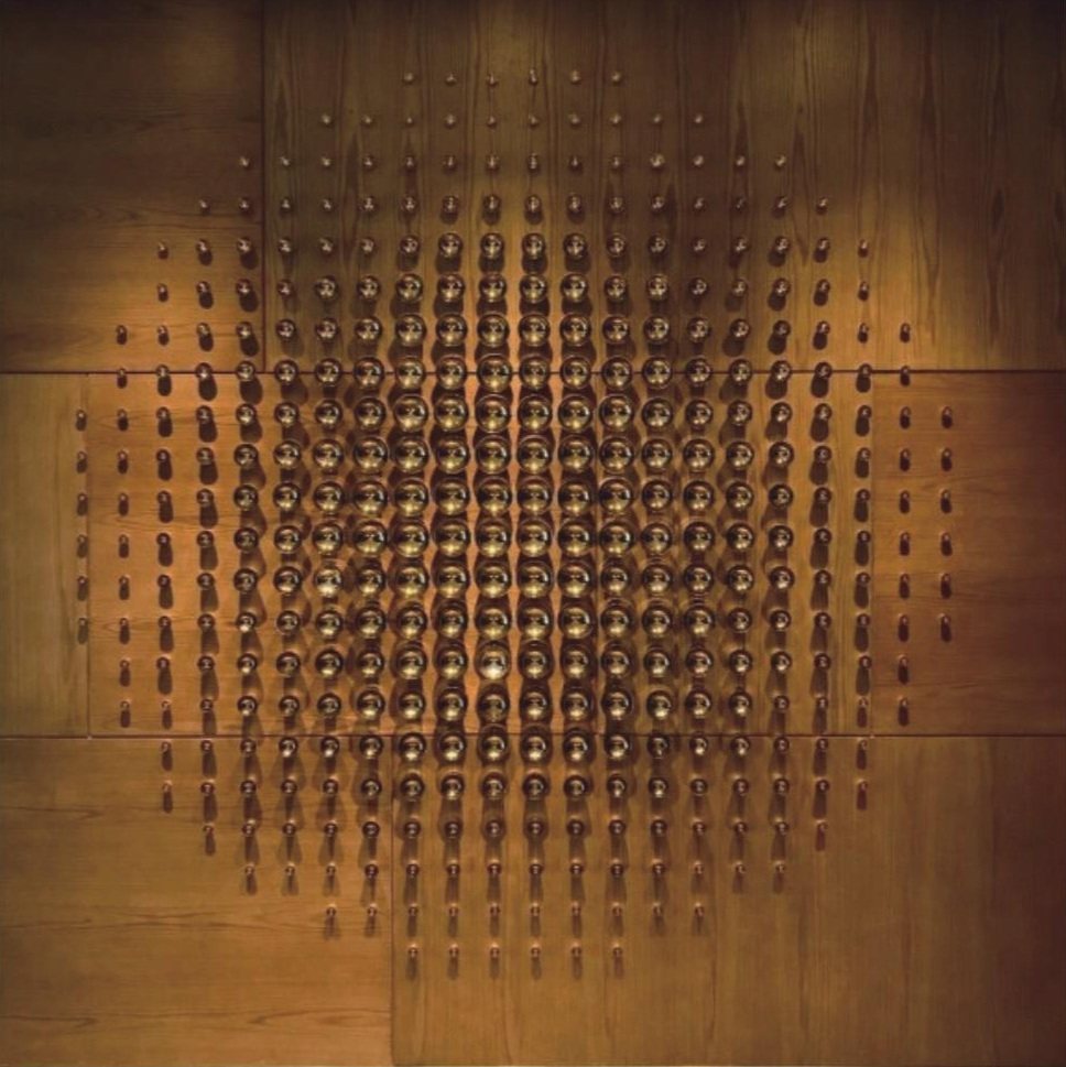 Bronze-tone wall relief arranged on a wood panel