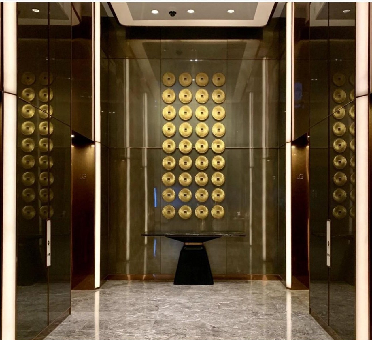 Repeated gold-tone wall art in a tall architectural bay