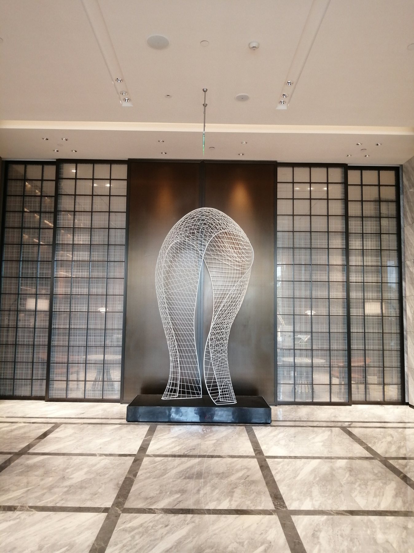 Wire-frame loop sculpture displayed in an interior lobby