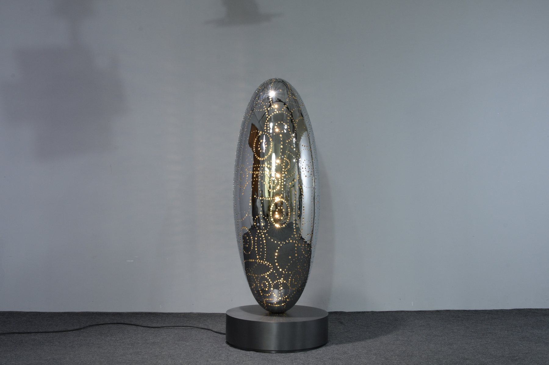 Tall oval illuminated sculpture on a circular base