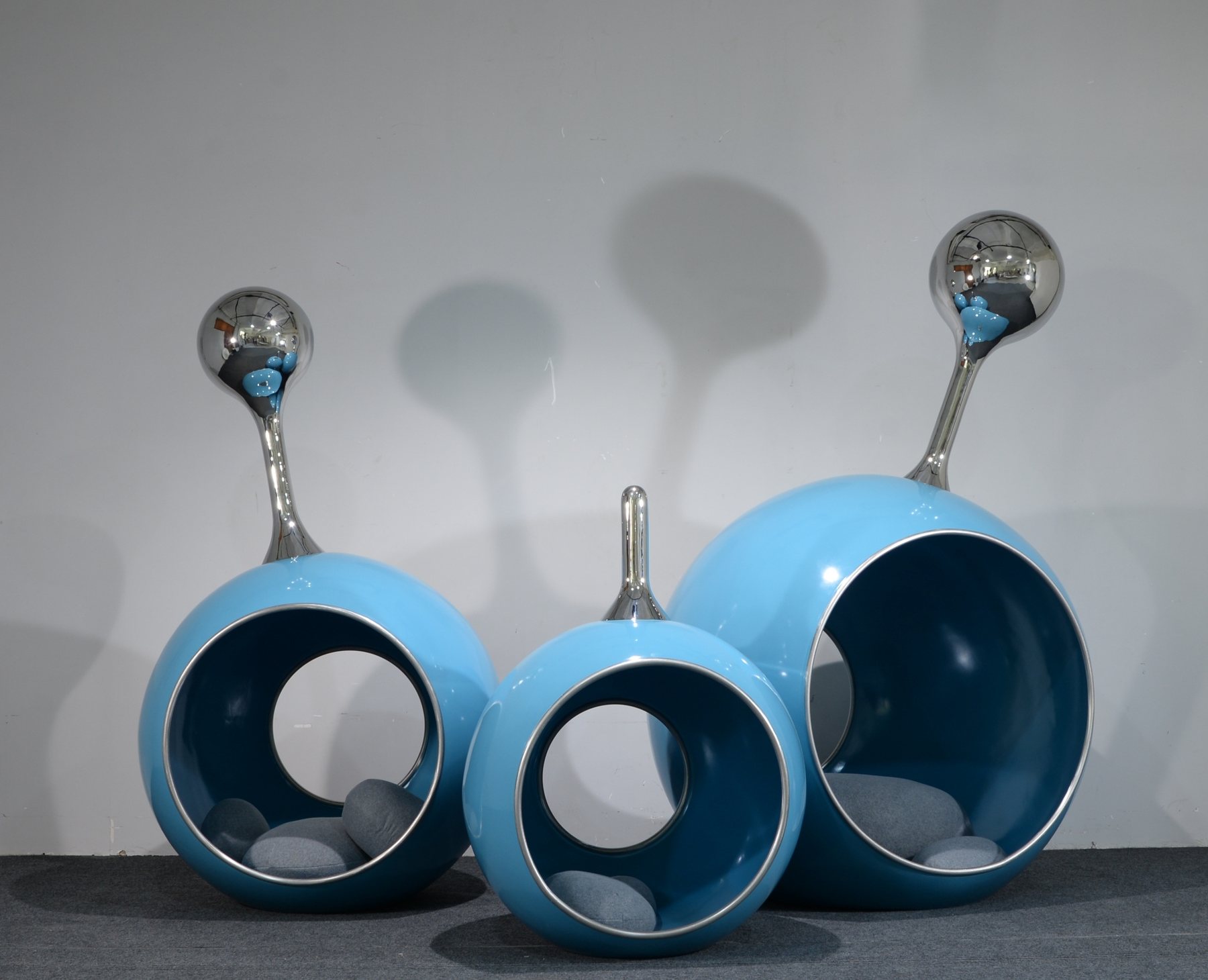 Three blue circular sculptural objects with reflective details