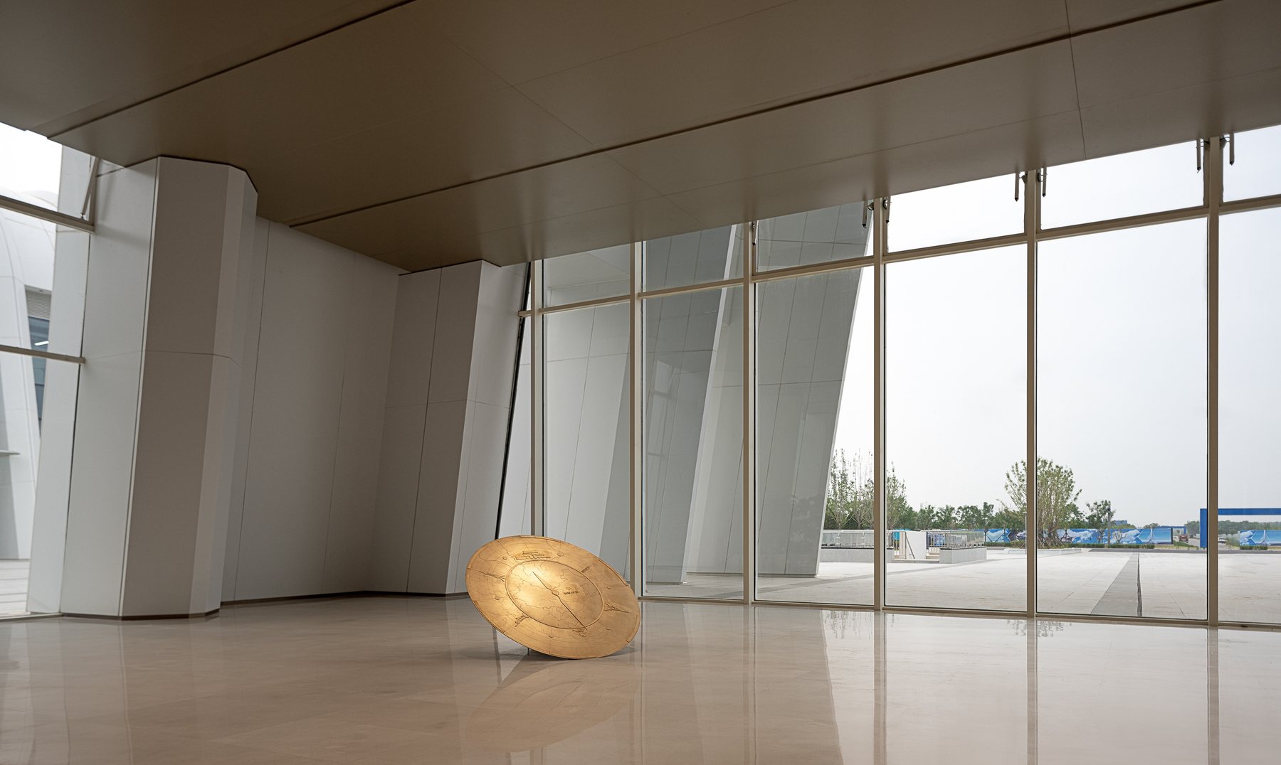 Gold-tone disc sculpture in a large interior