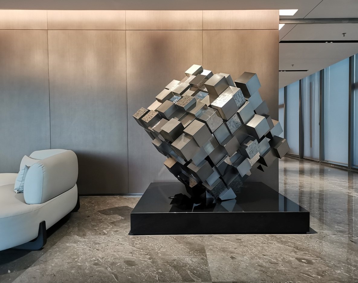 Large mirrored geometric sculpture beside hotel seating