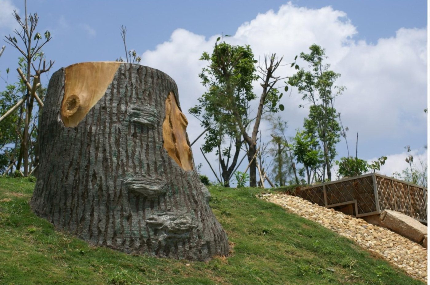 Tree-stump-inspired sculpture integrated with a green slope