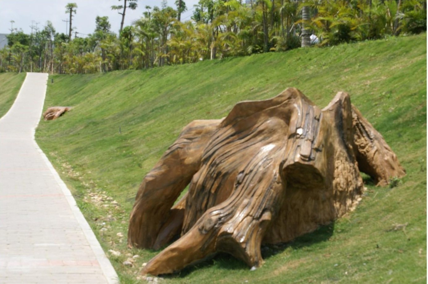 Wood-grain landscape sculpture beside a pedestrian path