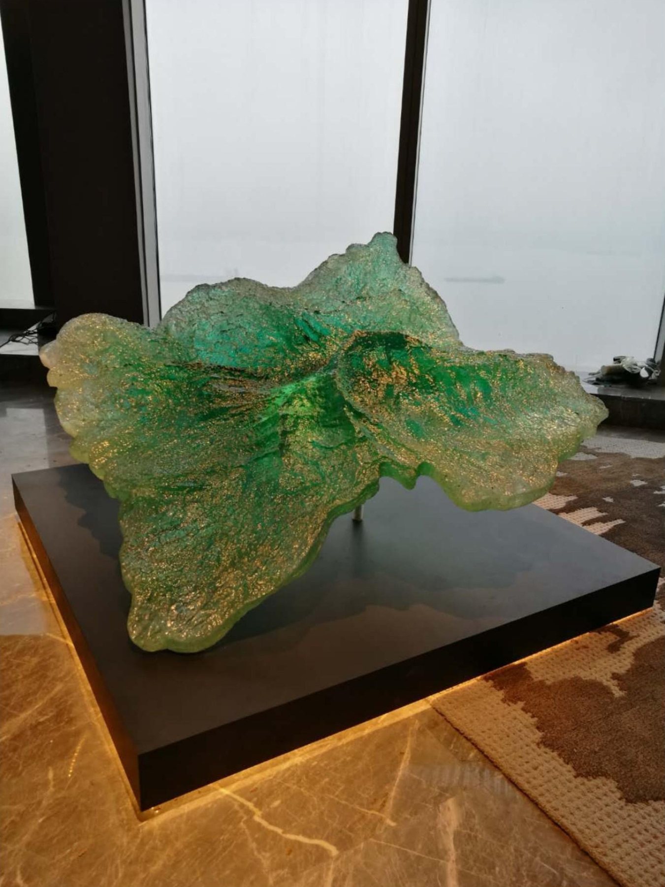 Close view of the translucent green artwork on a dark plinth