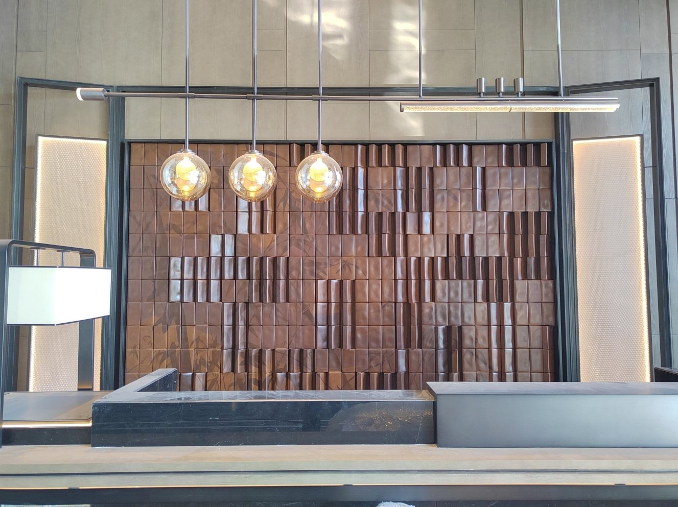 Bronze-tone feature wall aligned behind a hotel counter