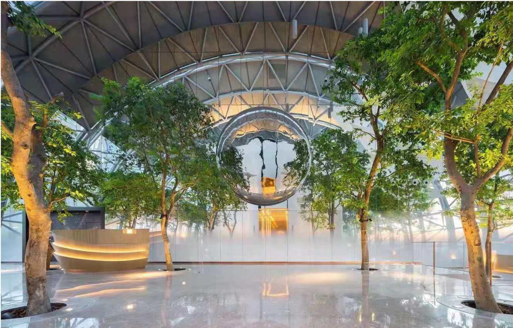 Large circular reflective art feature in a planted commercial atrium